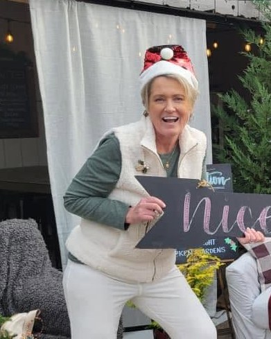 Mary in a Santa hat holding a Nice sign at Christmas
