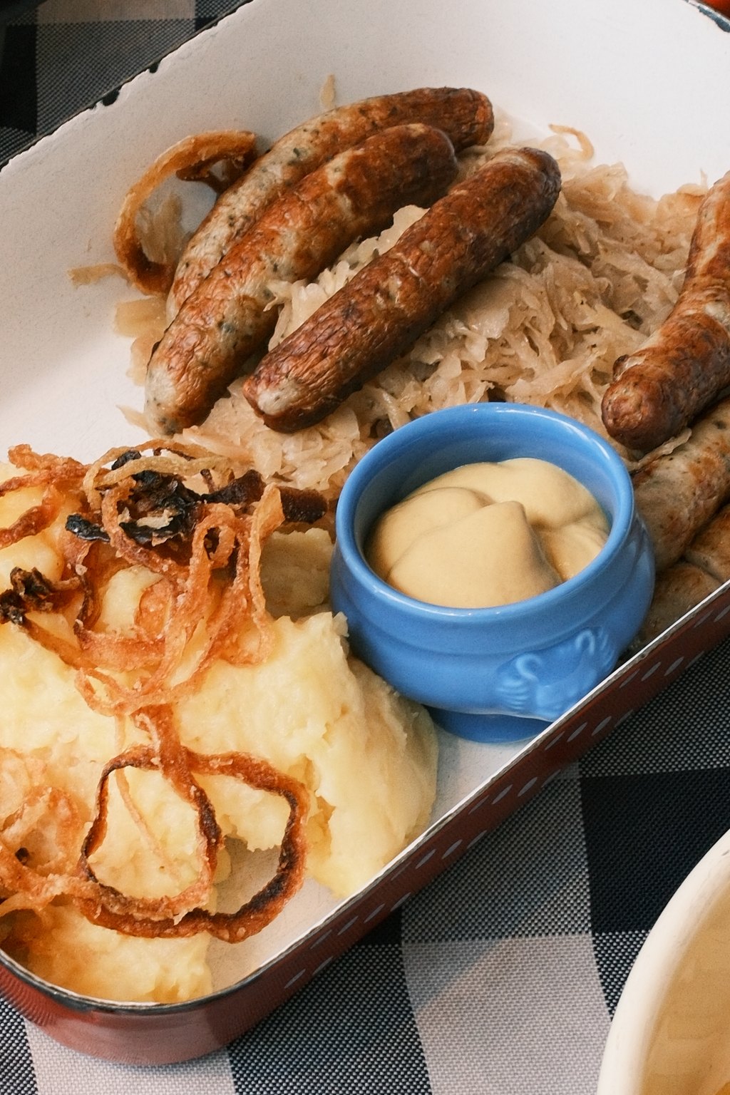Close up of sheet pan brats with sauerkraut and potatoes